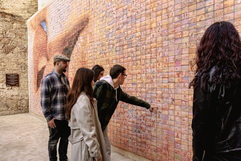 A group of people standing in front of a wall covered with photographs. 3