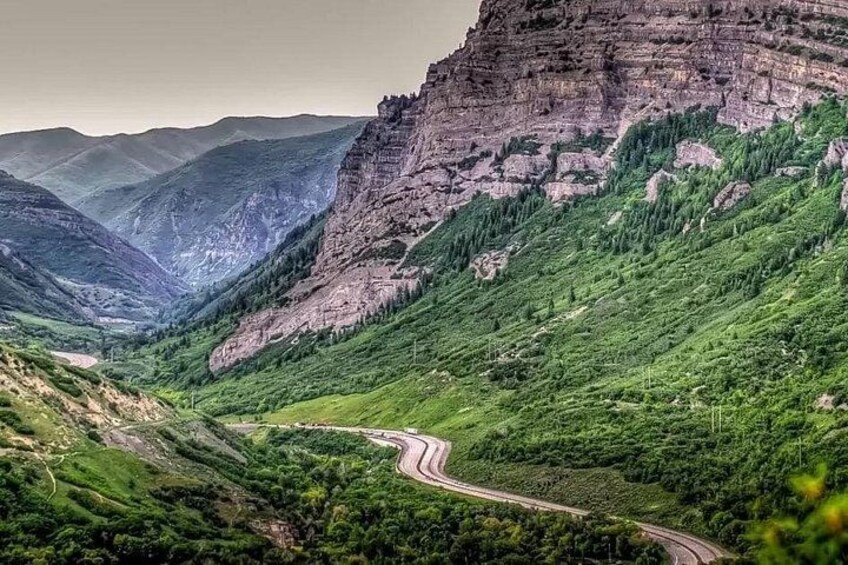 A winding road through a mountainous landscape with lush greenery and rocky cliffs. 3