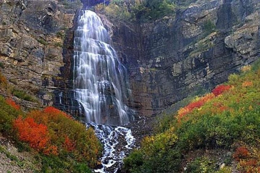 A waterfall cascading down a rocky cliff surrounded by autumn foliage. 2