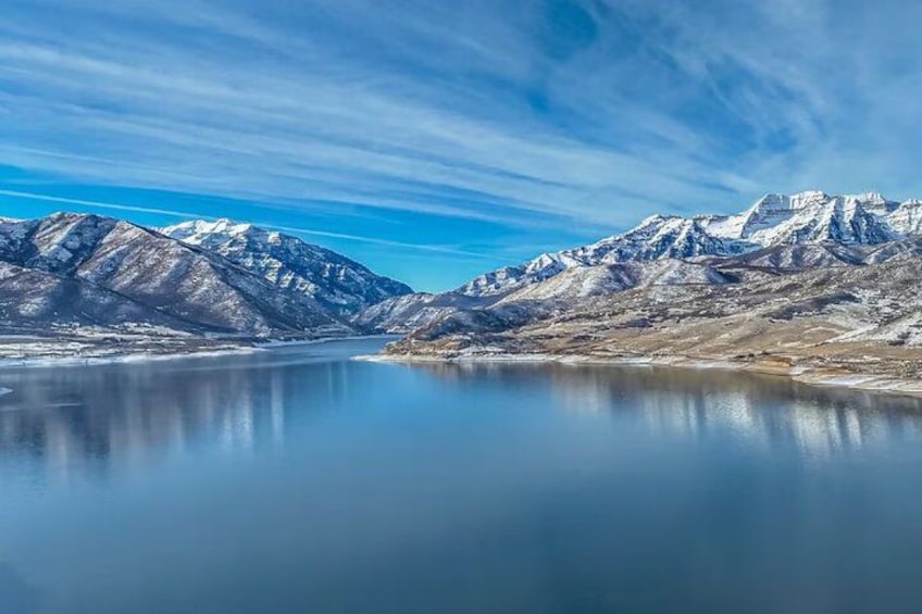 Ein Gebirge mit schneebedeckten Gipfeln und einem stillen See, der die Landschaft spiegelt. 5