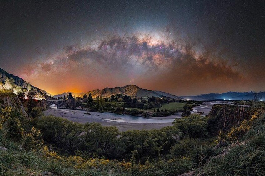 A river winding through a valley with mountains in the background and a starry sky above. 4