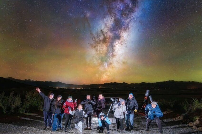 A group of people posing under a starry night sky with the Milky Way visible. 3