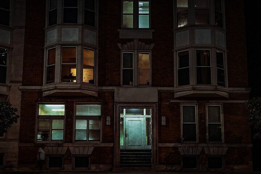 A multi-story building with bay windows and a lit entrance. 4