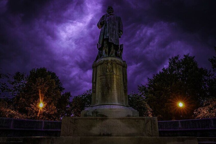 A statue at night with purple sky and streetlights. 5