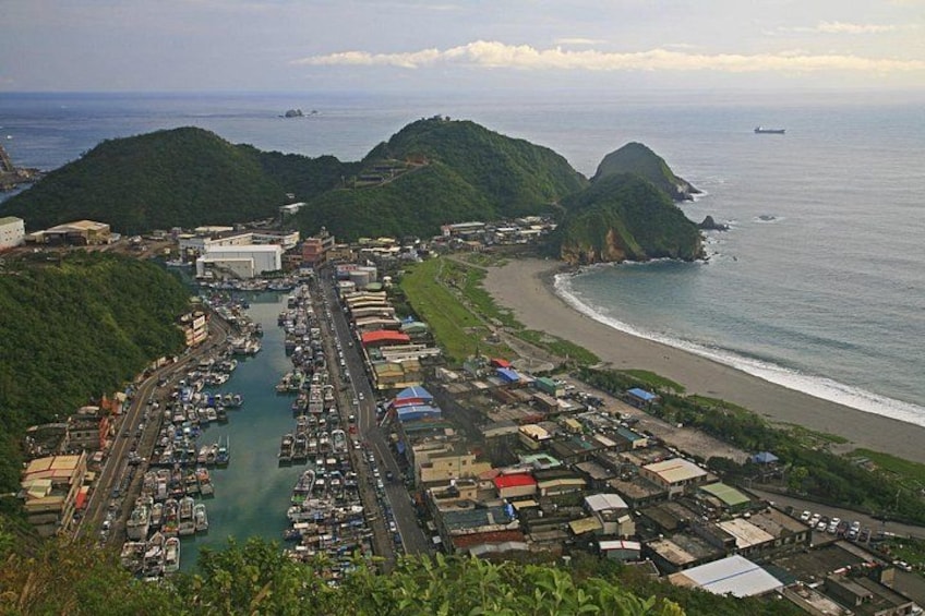A coastal town with a marina, buildings, and a beach. 1