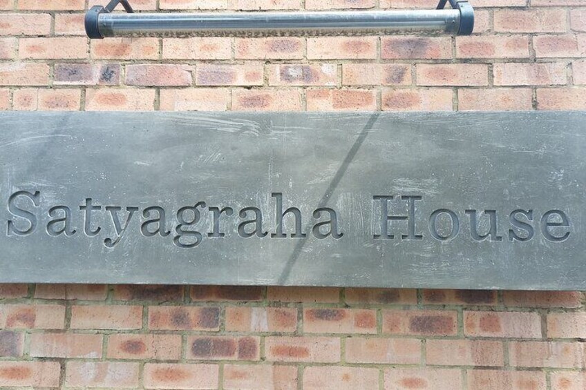 A sign for 'Satyagraha House' mounted on a brick wall. 4