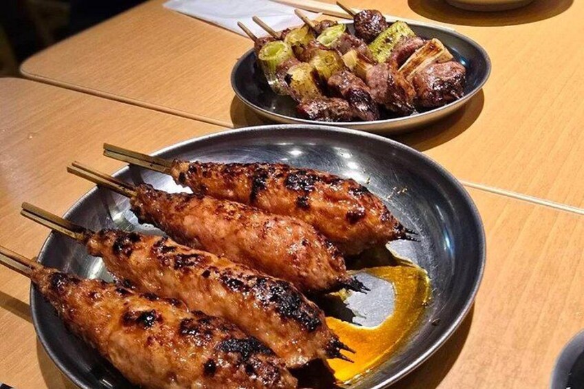 Grilled meat skewers on a metal plate, accompanied by a bowl of vegetables. 3