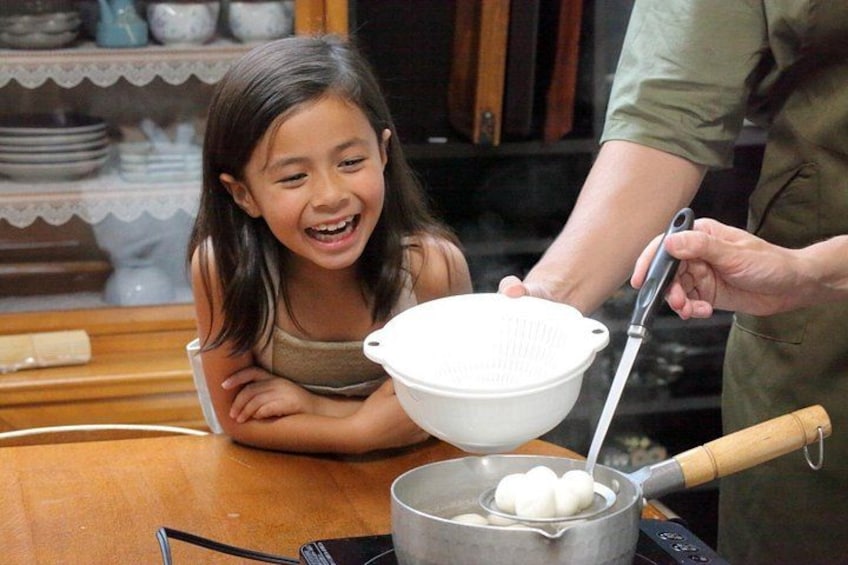 Una persona cocinando, con una olla sobre la estufa y un colador encima. 1