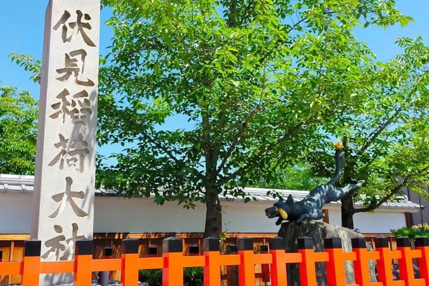 Una estatua de una persona en una pose dinámica, un edificio tradicional japonés y un cartel con caracteres japoneses. 3