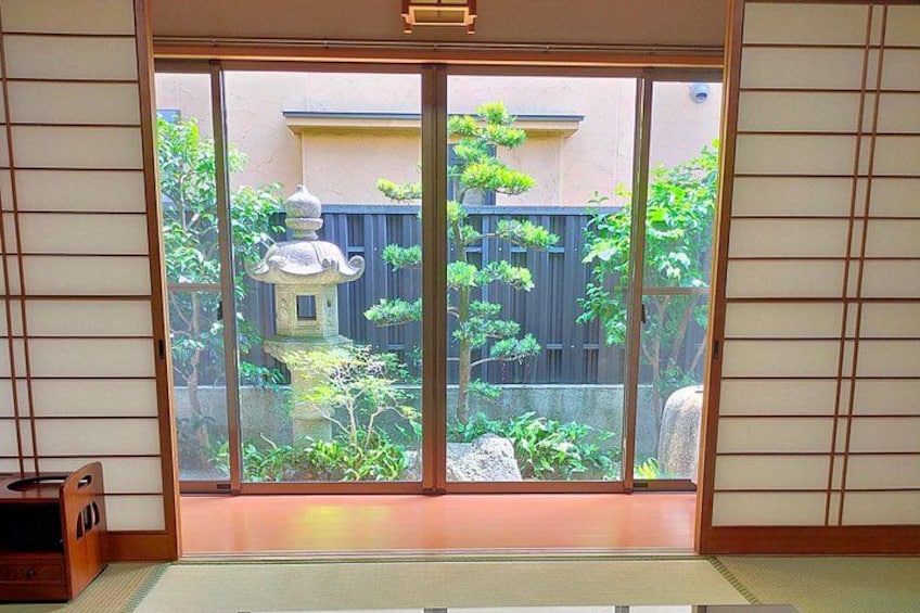Una puerta corrediza japonesa tradicional con vistas a un jardín, que incluye un farol de piedra y una valla de madera. 5