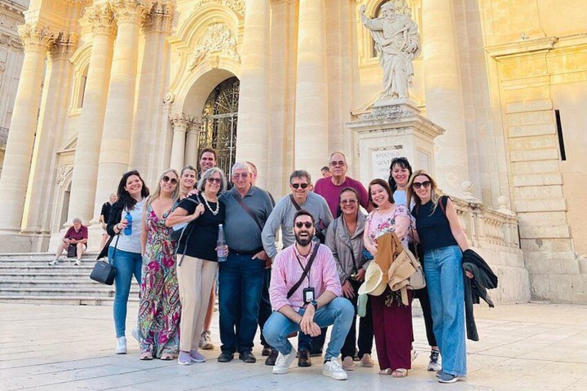 A group of people posing in front of a grand building with columns and a statue. 5