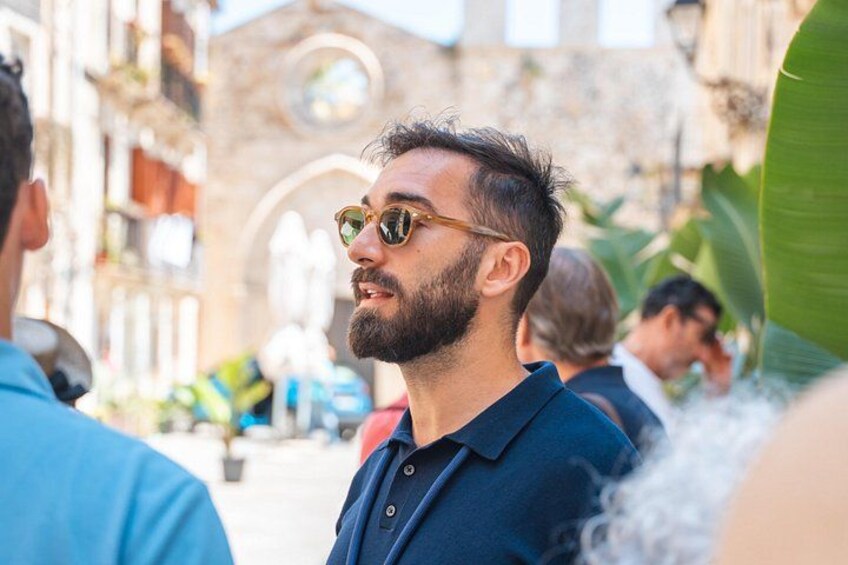 A man in a blue shirt standing outdoors with a building in the background. 2