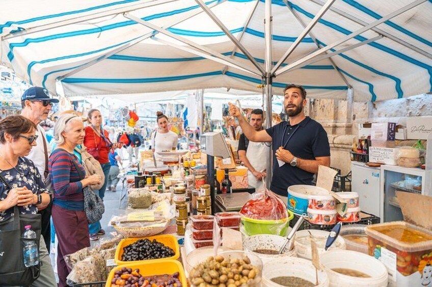 A market stall with various food items and a person serving customers. 3
