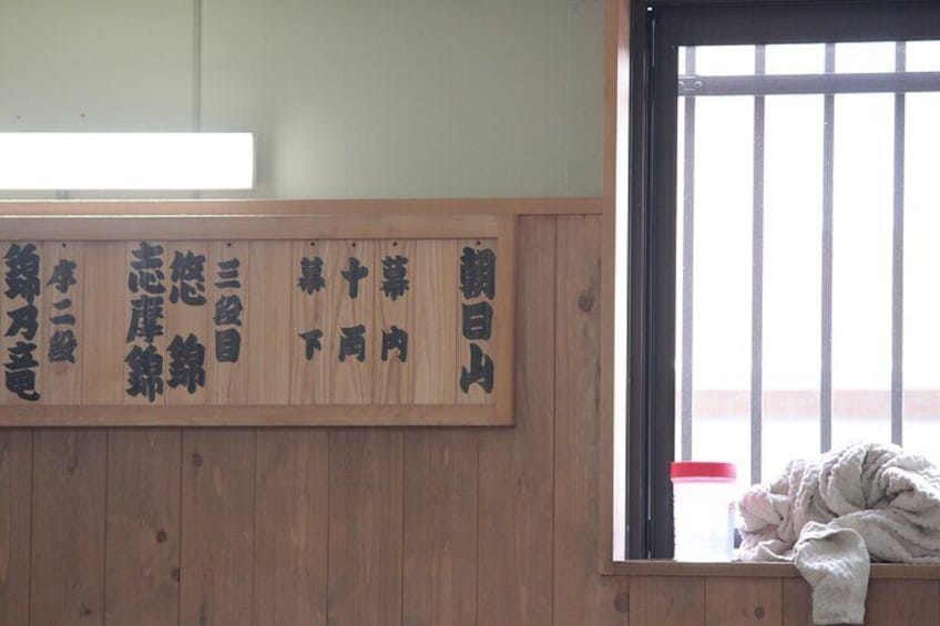 A wooden wall with Japanese calligraphy and a window with bars. 5