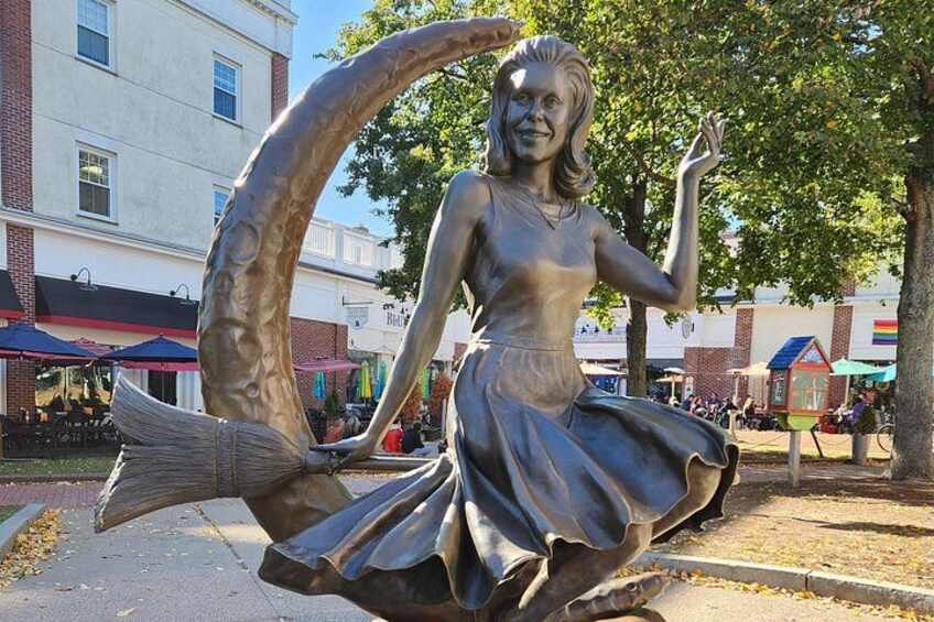 A statue of a woman with a fish tail, sitting on a curved bench in a public square. 4