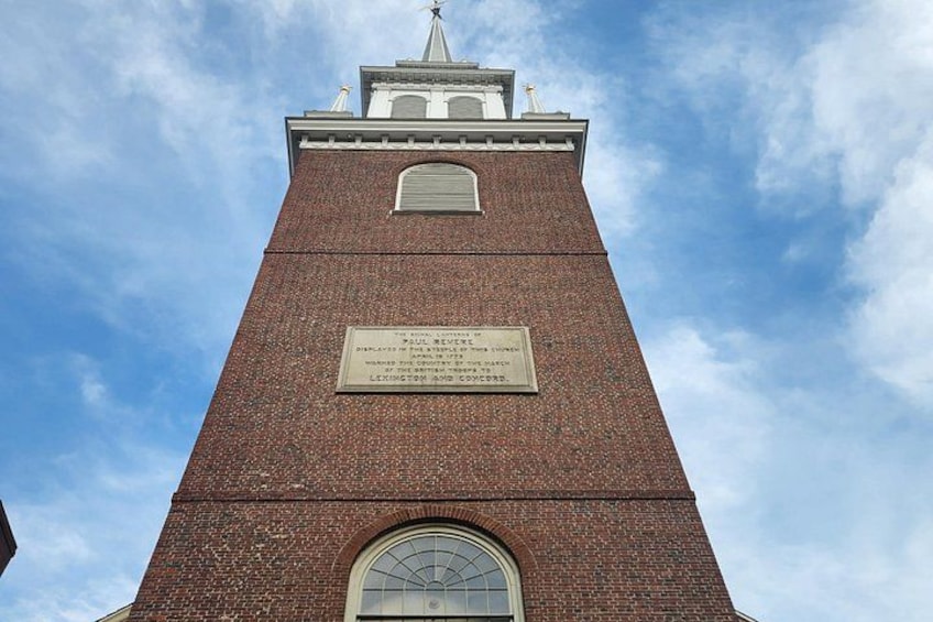 A tall brick tower with a clock and a plaque. 5