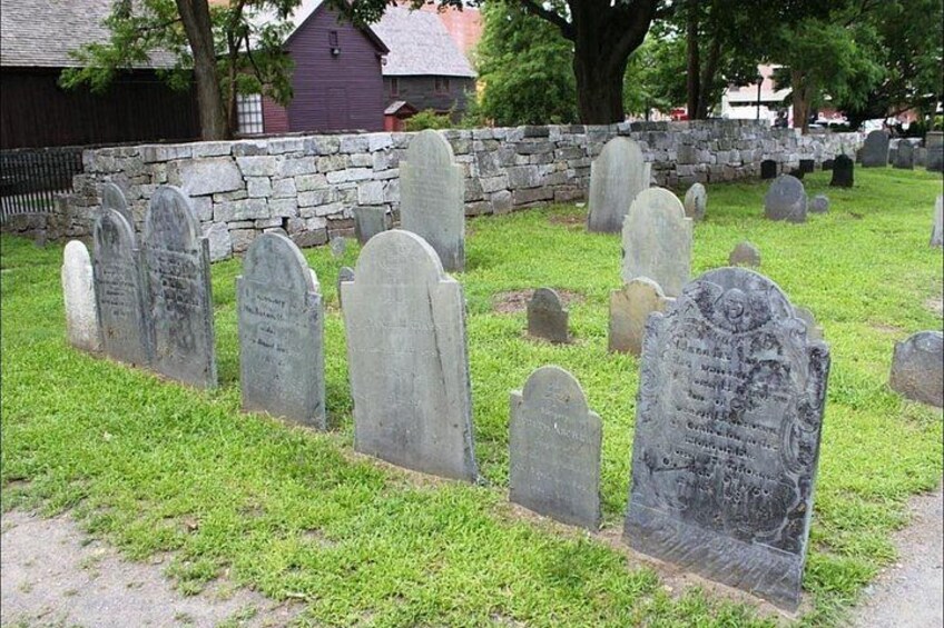 A cemetery with headstones and a stone wall in the background. 2