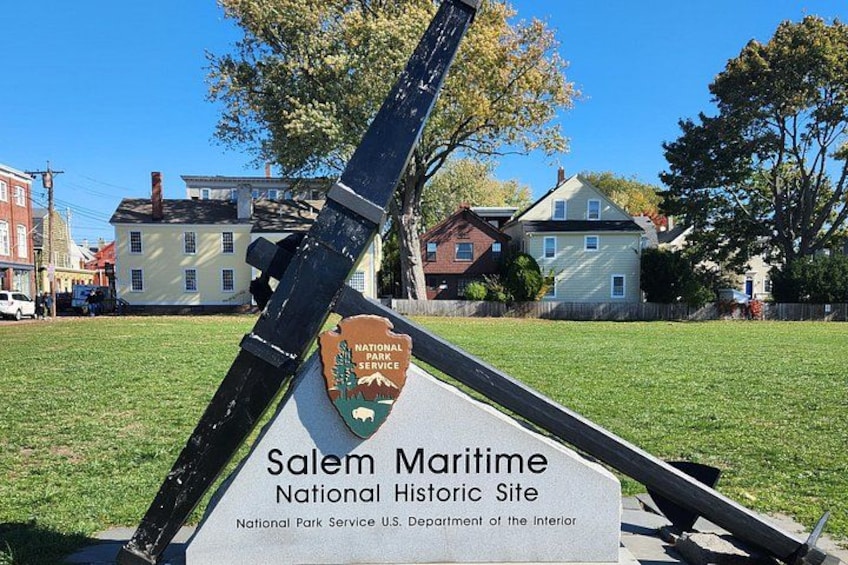A tilted sign for Salem Maritime National Historic Site with a backdrop of residential houses and a clear sky. 4
