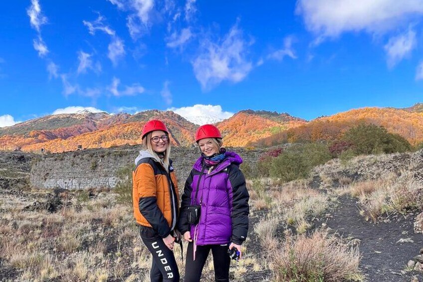 Two people wearing hats and jackets standing on a rocky path with a mountainous landscape in the background. 2