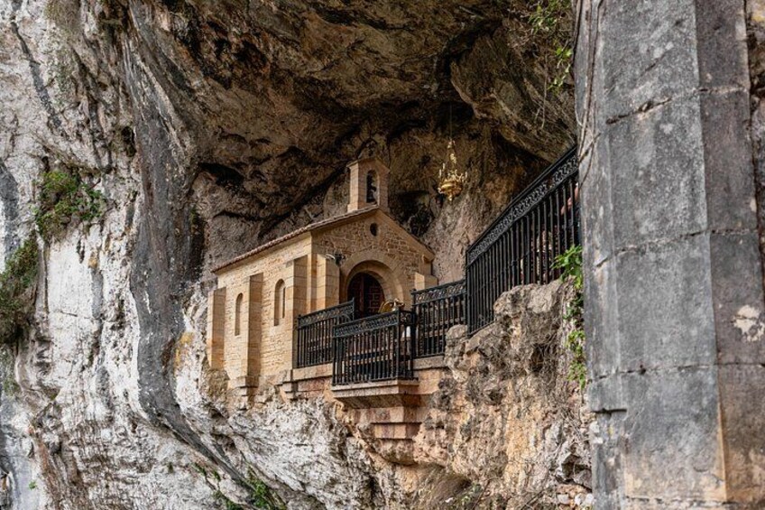 A church built into a rocky cliffside with a black iron railing. 2