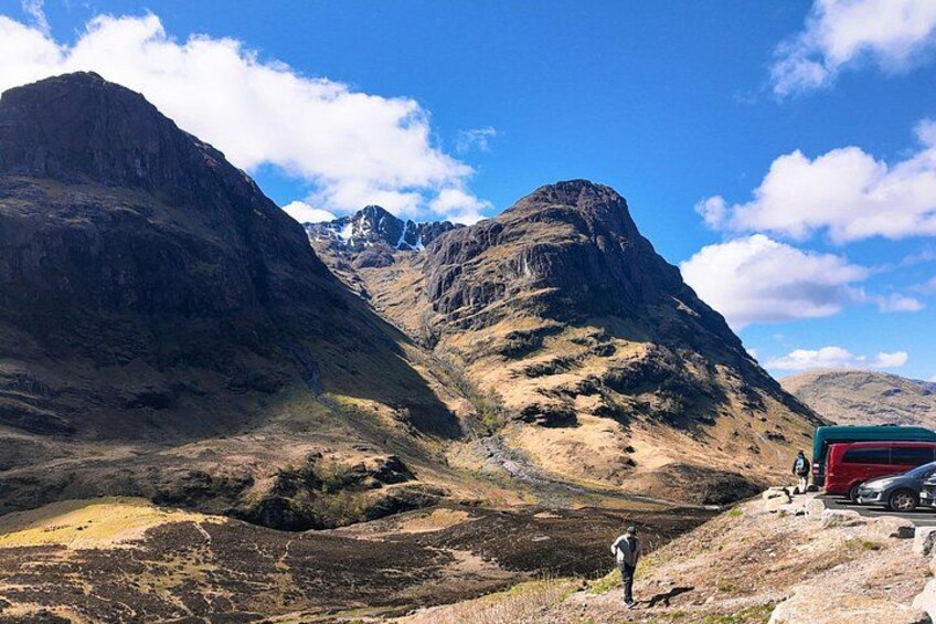 A mountainous landscape with a person standing near a red vehicle. 3