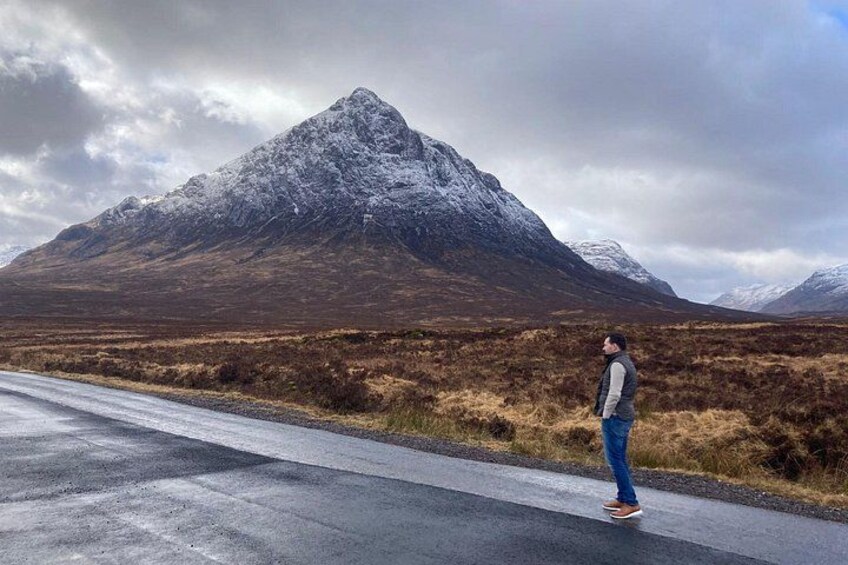 A person standing on a road with a mountain in the background. 2
