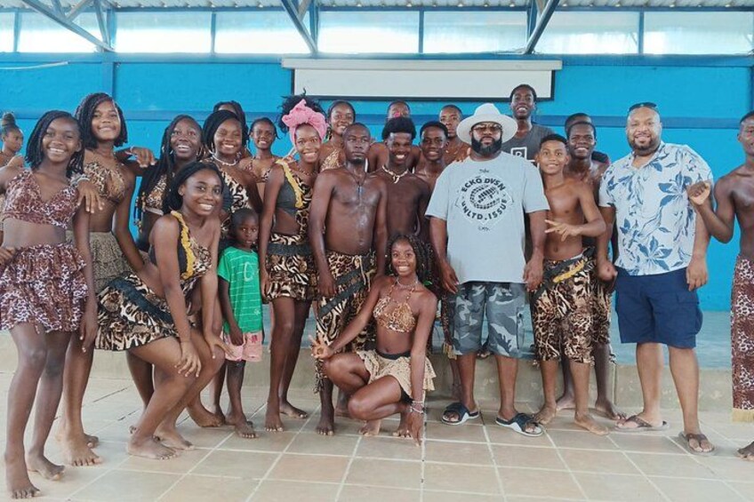 A group of people posing for a photo in a covered area with blue walls and tiled flooring. 5