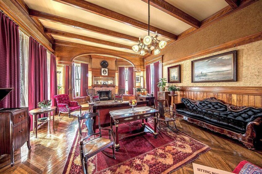 A spacious living room with a wooden ceiling, a large sofa, a dining table, and a fireplace. 3