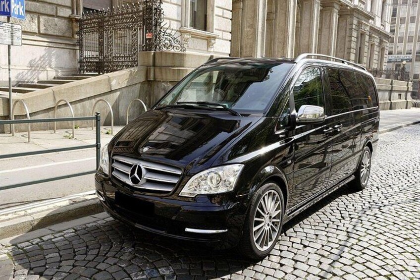 A black Mercedes-Benz van parked on a cobblestone street in front of a building with classical architecture. 2