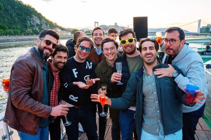 A group of people on a boat with a river and a bridge in the background. 3