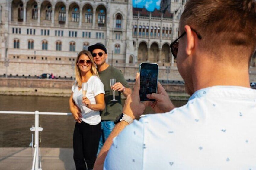 A couple standing by a river with a historic building in the background. 3