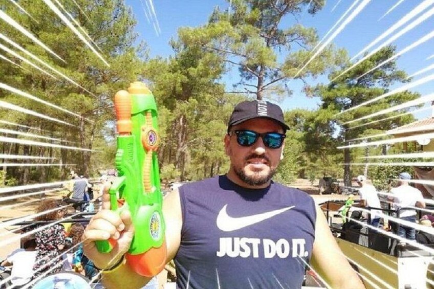 A person holding a green water gun, wearing a sleeveless shirt with 'JUST DO IT.' text, and a cap. 1