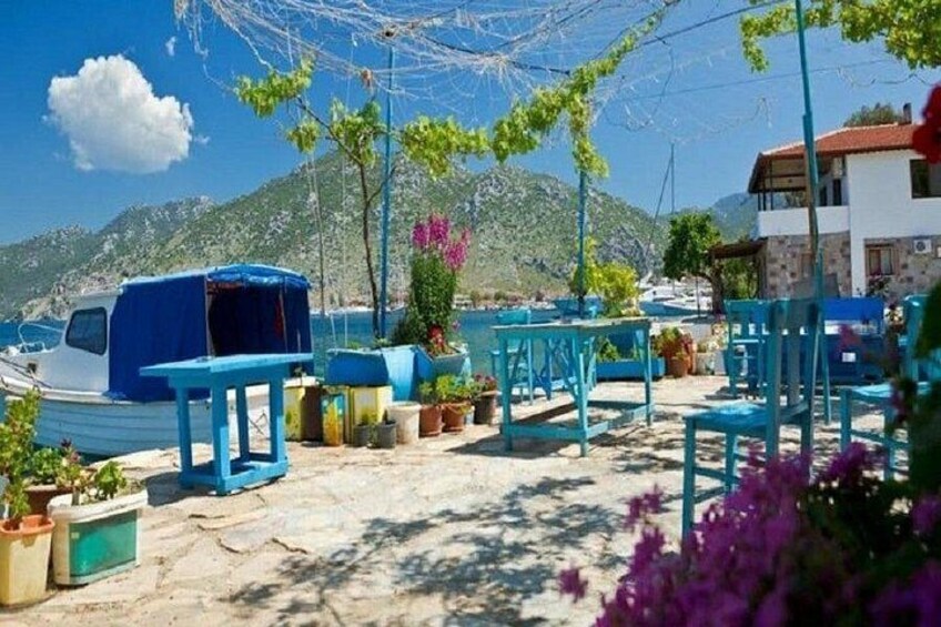 A beachside café with blue furniture, potted plants, and a boat in the background. 3