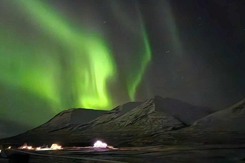 Auroras boreales sobre un paisaje montañoso con una fogata. 1