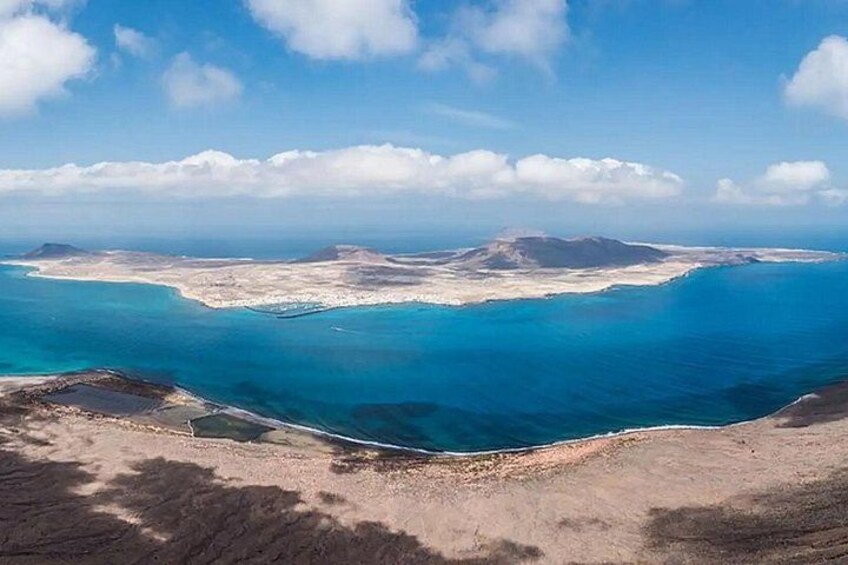 A coastal landscape with a clear blue sea, sandy beaches, and distant mountains. 2