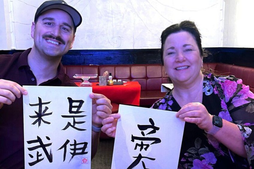 Two people holding signs with Japanese characters. 2