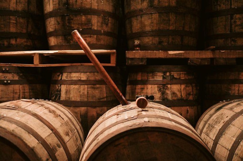 Wooden barrels with metal hoops, stacked in a row. 2