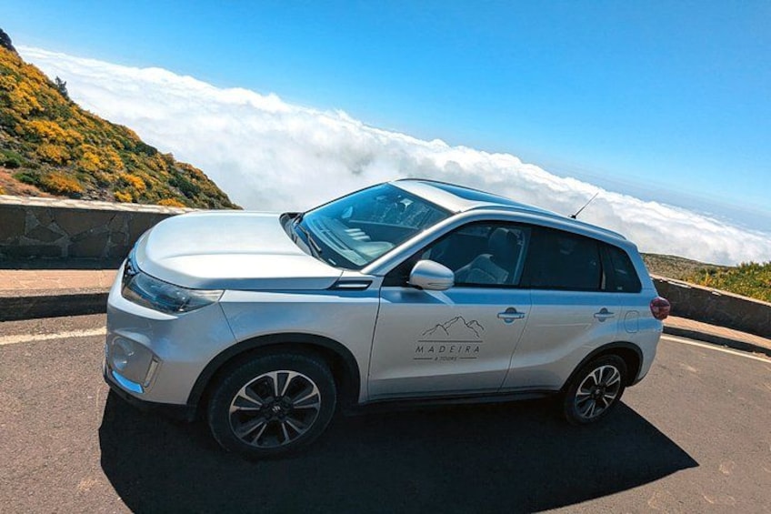 A white SUV parked on a road with a mountainous landscape in the background. 1