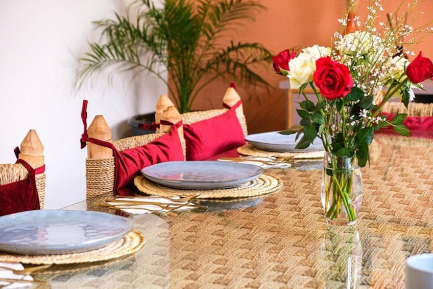 Une table dressée avec des assiettes, un vase de fleurs et des coussins décoratifs. 2