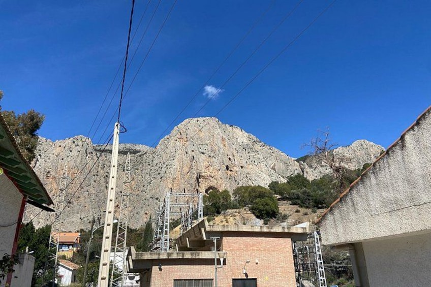Un paisaje montañoso con cielo despejado, un edificio de techo rojo y un poste de electricidad. 3