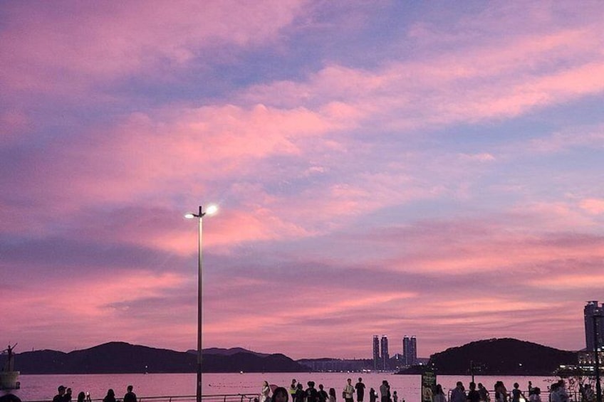 Solnedgang over vand med silhuetter af mennesker og bygninger i baggrunden. 1
