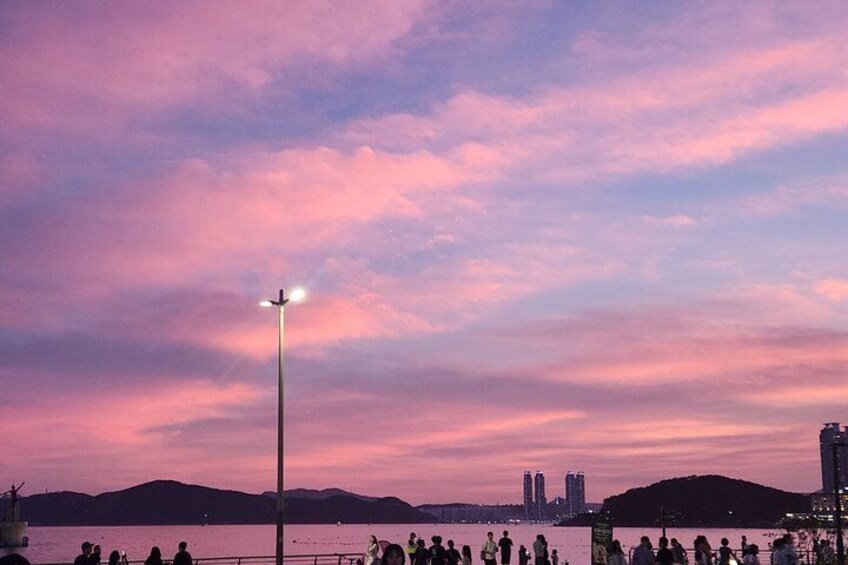Un atardecer sobre una masa de agua con siluetas de personas y un farol. 2