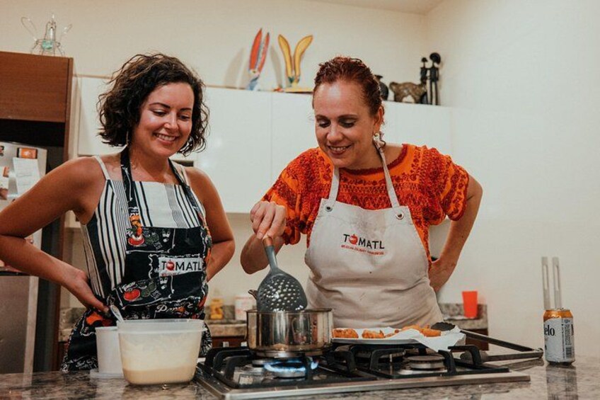 Dos personas cocinando en una cocina con estufa, una olla y un rallador. 1