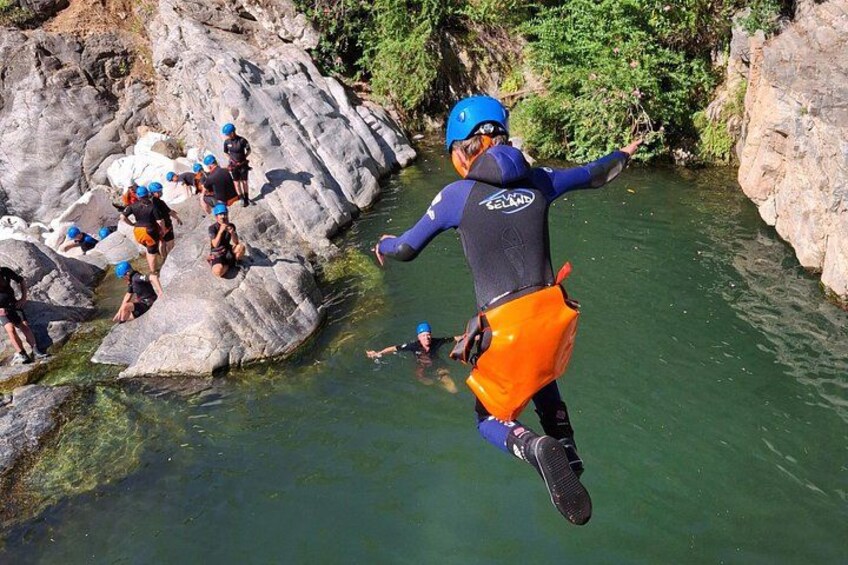 A group of people engaged in a water-based activity, possibly kayaking or rafting, in a rocky river environment. 5