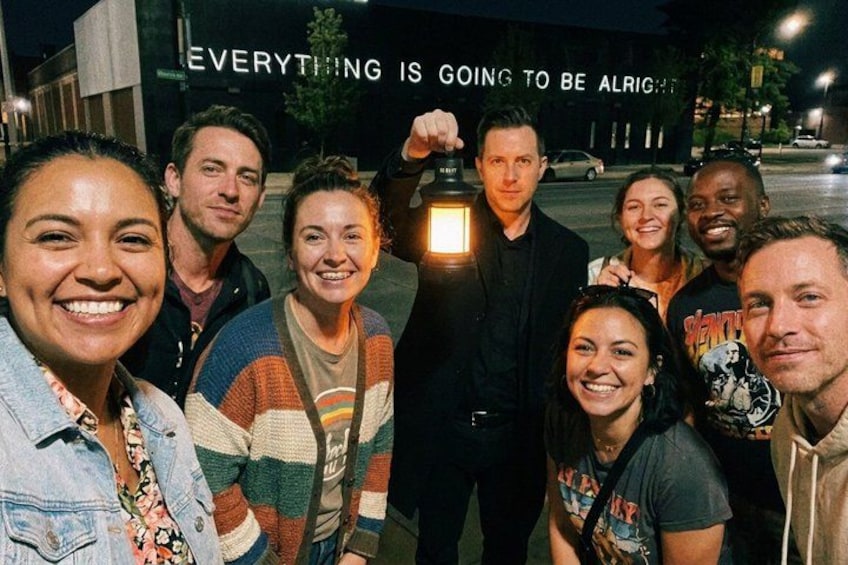 A group of people posing in front of a building with illuminated text. 5