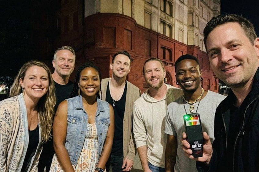 A group of people standing in front of a building at night. 1