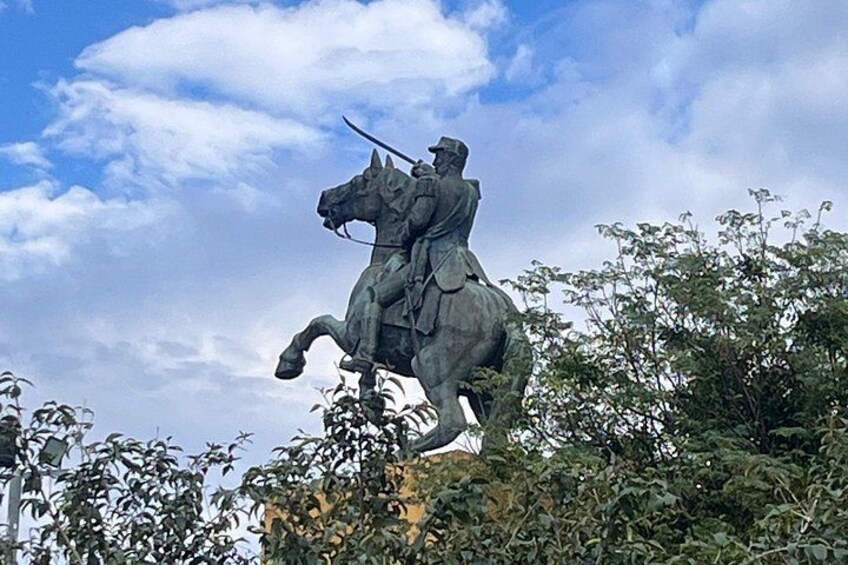 A statue of a mounted figure on a pedestal, surrounded by foliage. 2