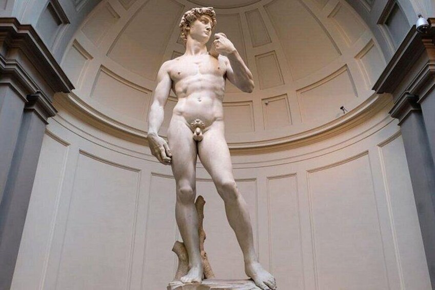 A marble statue of a male figure with a muscular build, standing on a pedestal, in a classical architectural setting with a domed ceiling and columns. 1