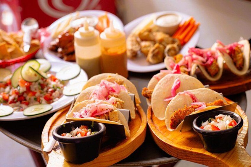 Forskellige tacos og tilbehør anrettet på træfade. 2