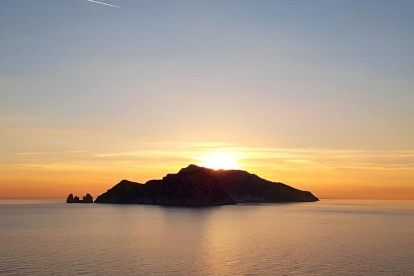 Tramonto sul mare calmo con la sagoma di una piccola isola. 3